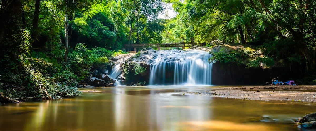 Beautiful waterfall Mae Sa, Thailand. Fresh and pure water stream is flowing on the rock stone ground in tropical rainforest. Fresh plants and trees above river. Vibrant colors in pure nature