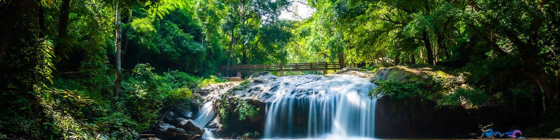 Beautiful waterfall Mae Sa, Thailand. Fresh and pure water stream is flowing on the rock stone ground in tropical rainforest. Fresh plants and trees above river. Vibrant colors in pure nature