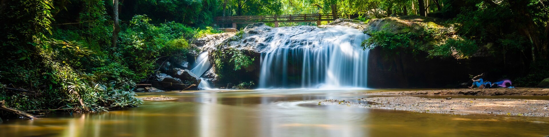 Beautiful waterfall Mae Sa, Thailand. Fresh and pure water stream is flowing on the rock stone ground in tropical rainforest. Fresh plants and trees above river. Vibrant colors in pure nature