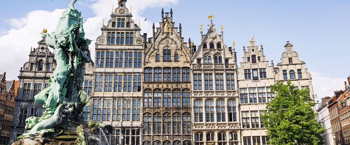 A historic building with ornate architecture and a large bronze statue in front.