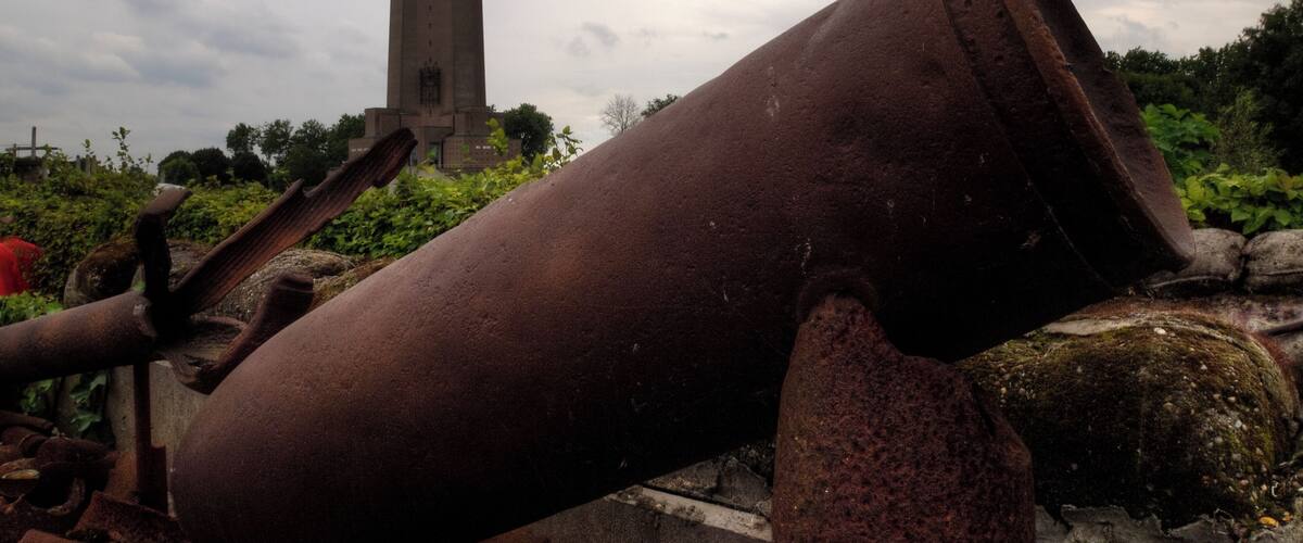 A rusted cylindrical object and a tall tower in the background.