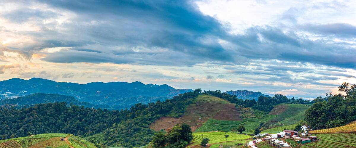 Panorama view , Morning mist over the mountain range during the rainy season of the hill where the vegetable garden is planted in steps on the mountain of Doi Mon Cham, Chiang Mai, Thailand.