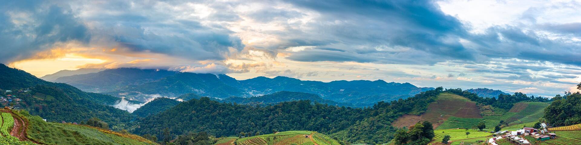 Terraced tea plantations, a mountain range, and a village.