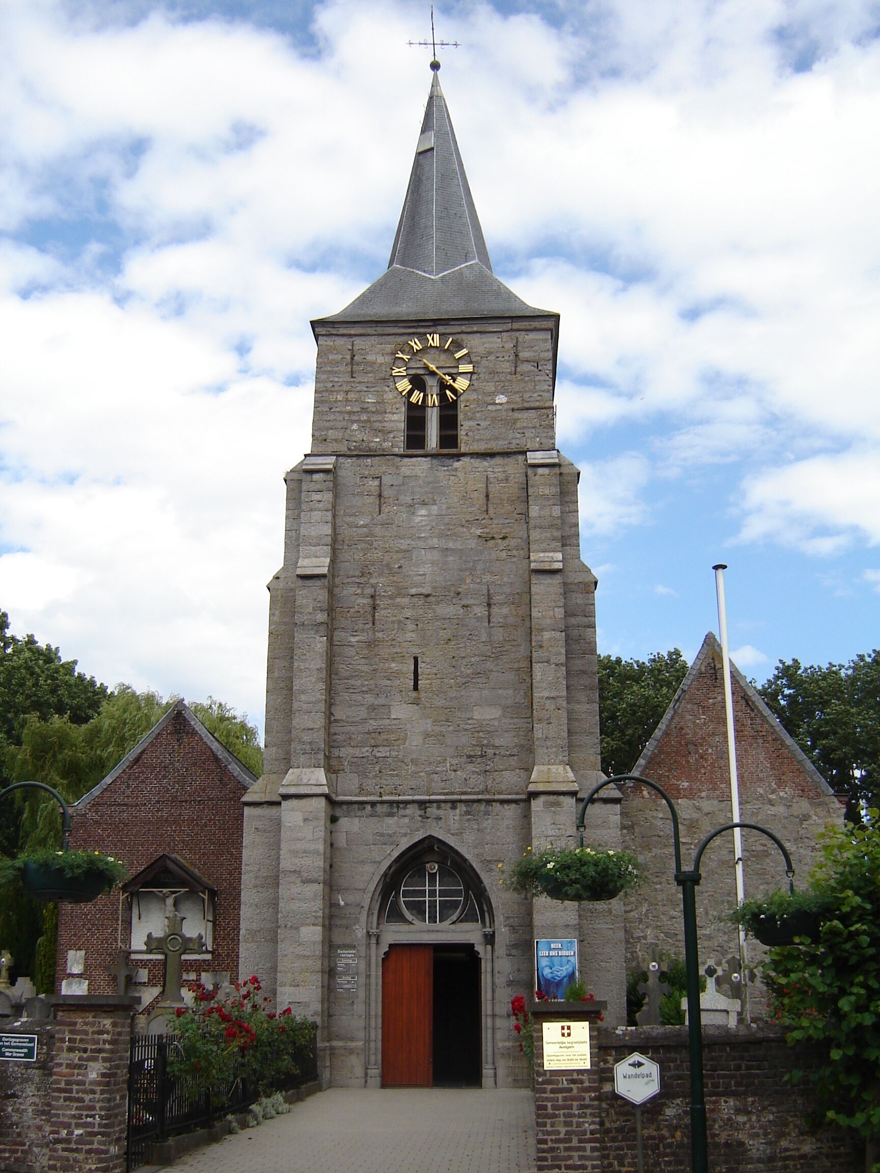 A church with a clock tower, a wooden door, and a sign that reads "Wandelpad".