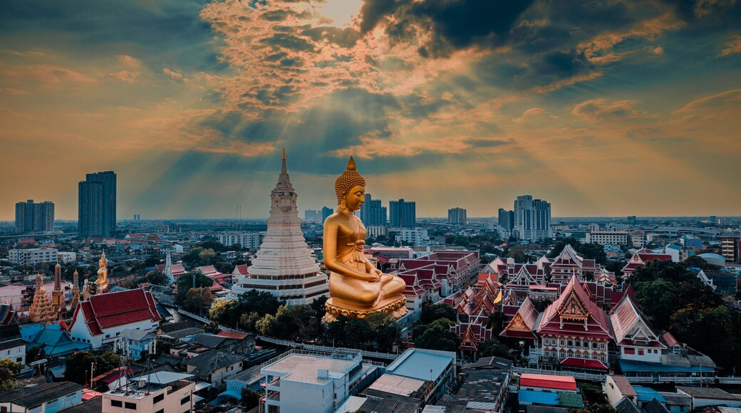 A large golden Buddha statue, a white stupa, and a cityscape with traditional buildings.