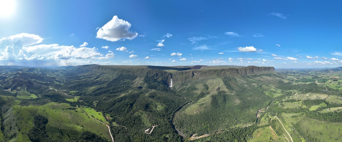 Aerial view of Serra da Canastra featuring the Casca d'Anta waterfall amidst lush green hills and winding roads in Sao Roque de Minas, Minas Gerais, Brazil.