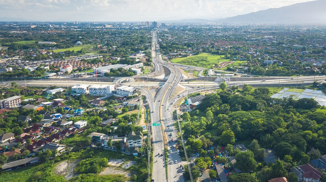 Aerial view of Mae Kuang intersection in San Sai, Chiang Mai, Thailand, showing multilane highway, overpass, moving traffic and transport infrastructure connecting suburban communities and routes.