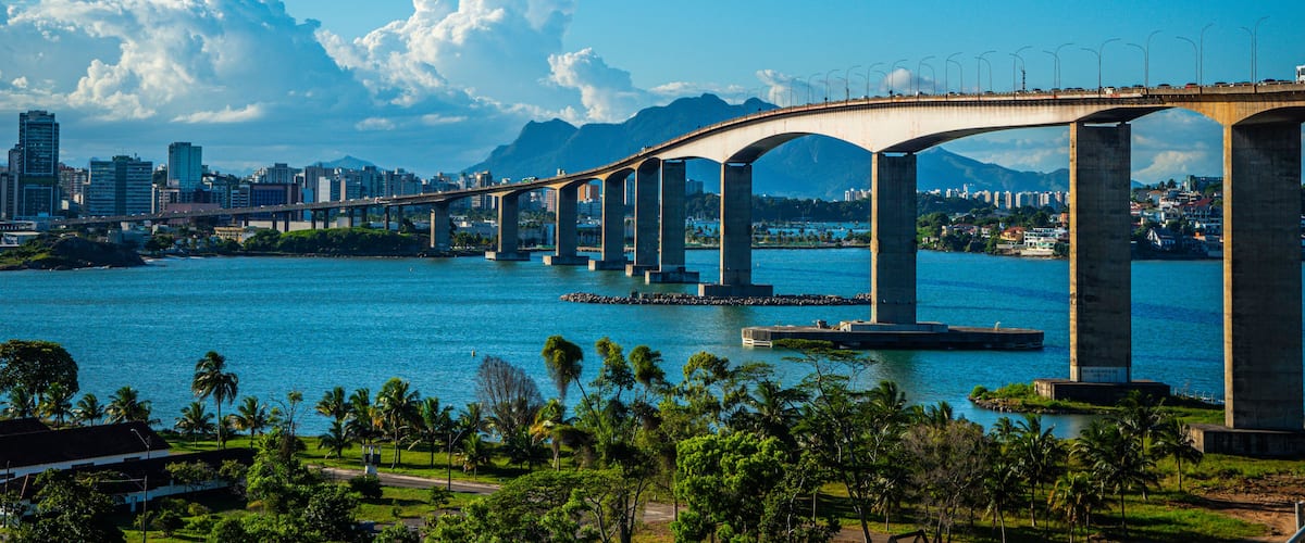 Uma ponte sobre a água, com um horizonte urbano ao fundo.