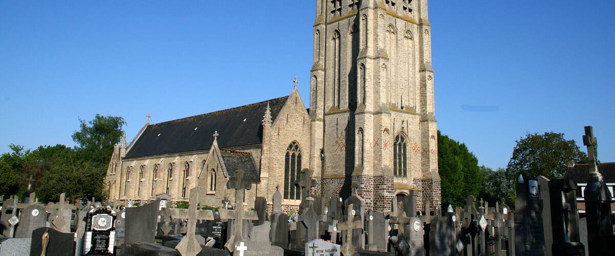 A historic church with a tall tower and numerous gravestones in the foreground.