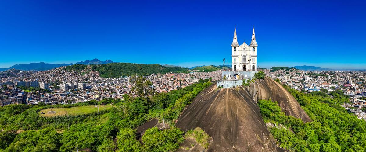 Una catedral con dos torres, rodeada por una ciudad densamente poblada y colinas verdes al fondo.