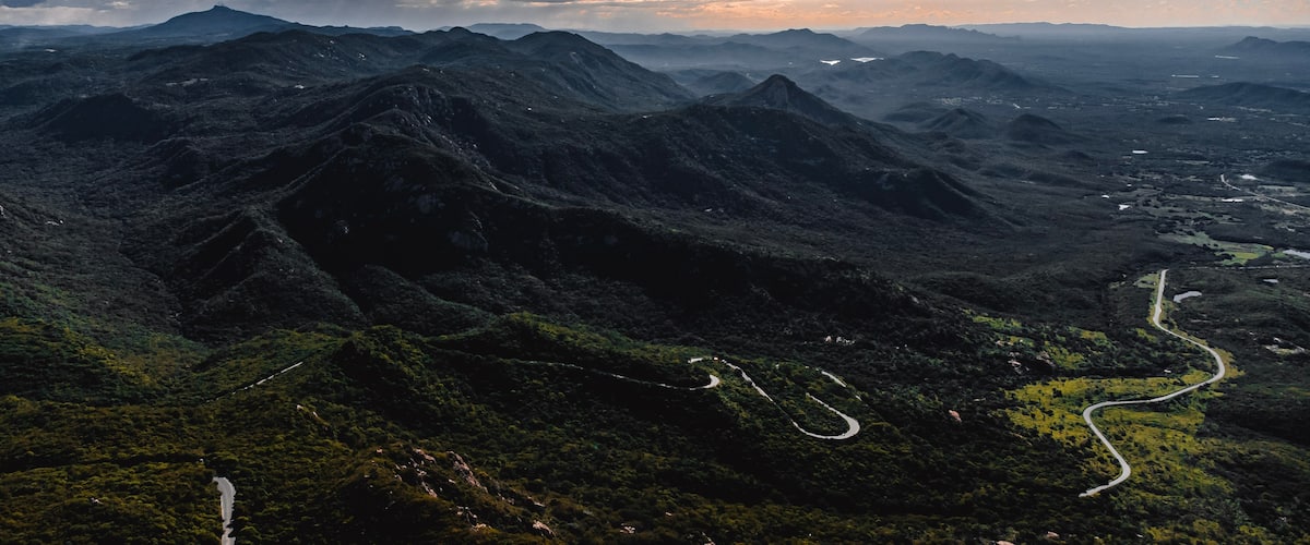 Paisagem montanhosa com estradas sinuosas e um rio.