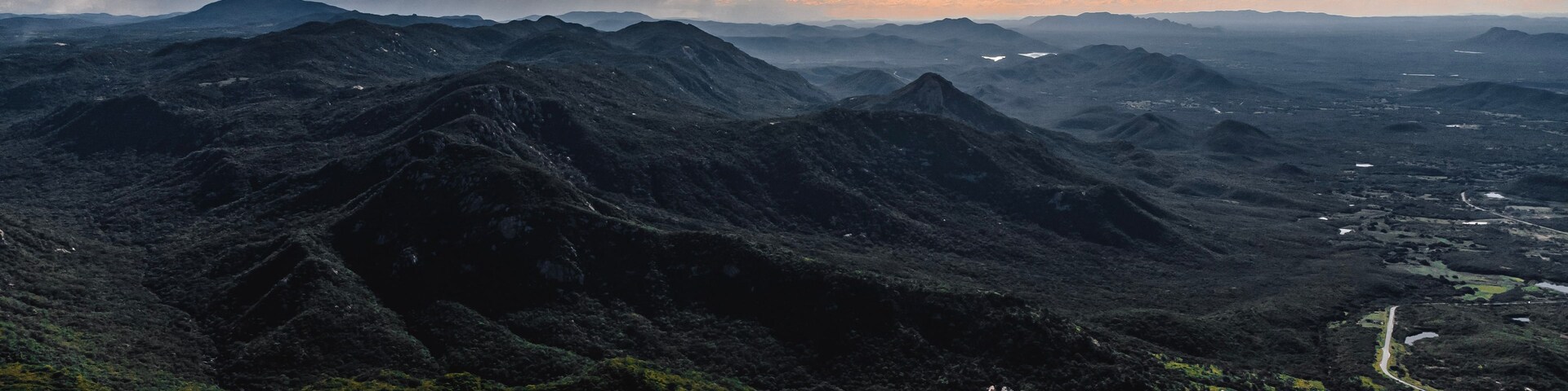 Paisagem montanhosa com estradas sinuosas e um rio.