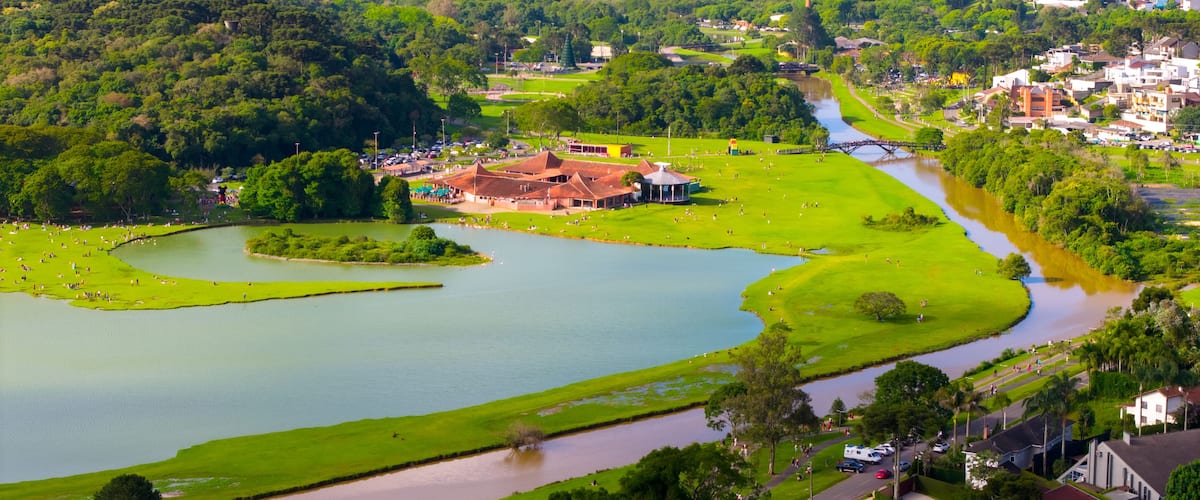 A river meandering through a park with a bridge, surrounded by lush greenery and residential areas.