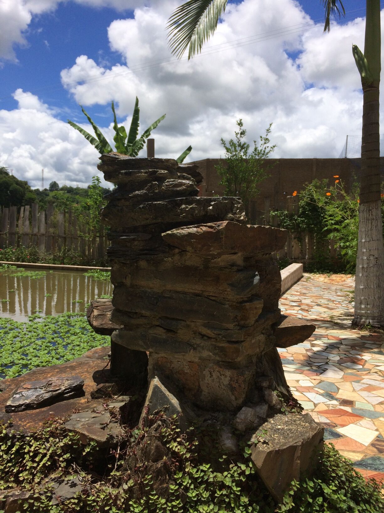 A rock formation with a pond and a tiled pathway.