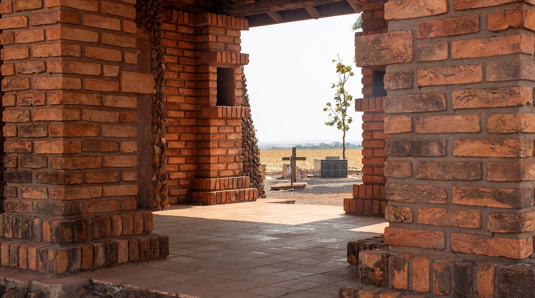 A brick structure with a cross and a tree in the background.