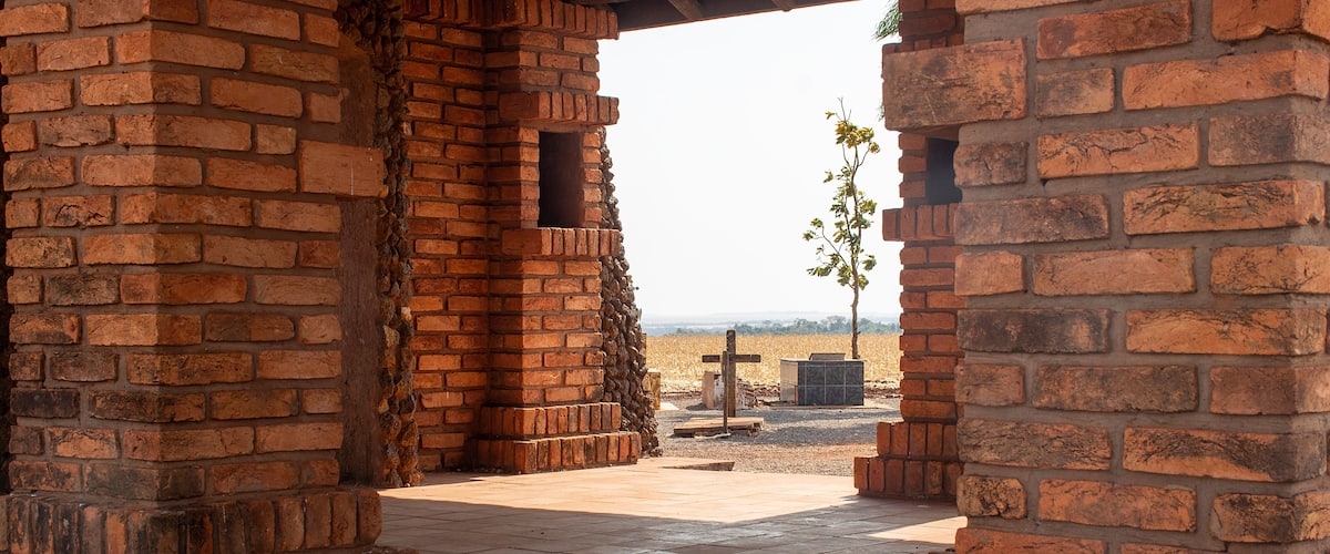 A brick structure with a cross and a tree in the background.