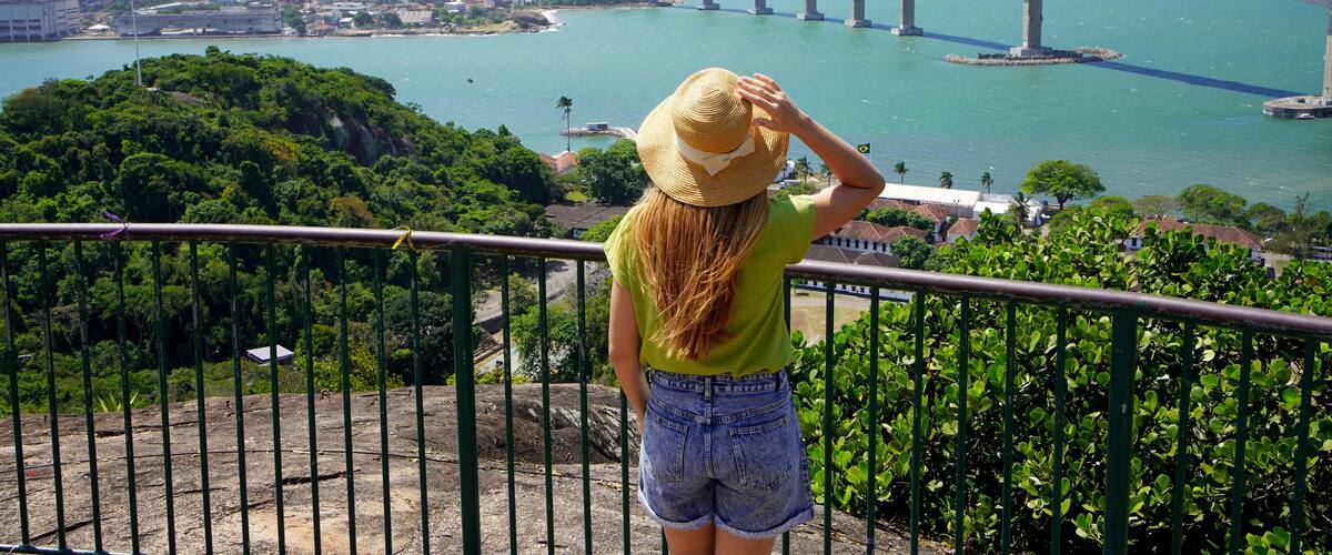 Holidays in Brazil. Back view of young traveler woman enjoying Vitoria cityscape with Terceira Ponte bridge, Vitoria, Espirito Santo, Brazil.