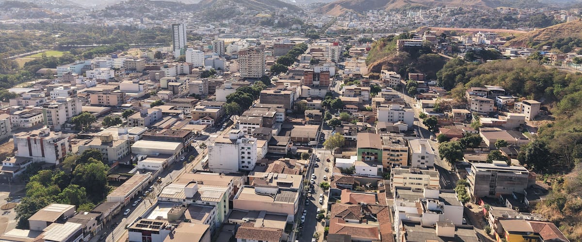 Uma cidade densamente construída, com um edifício alto imponente e colinas ao redor.