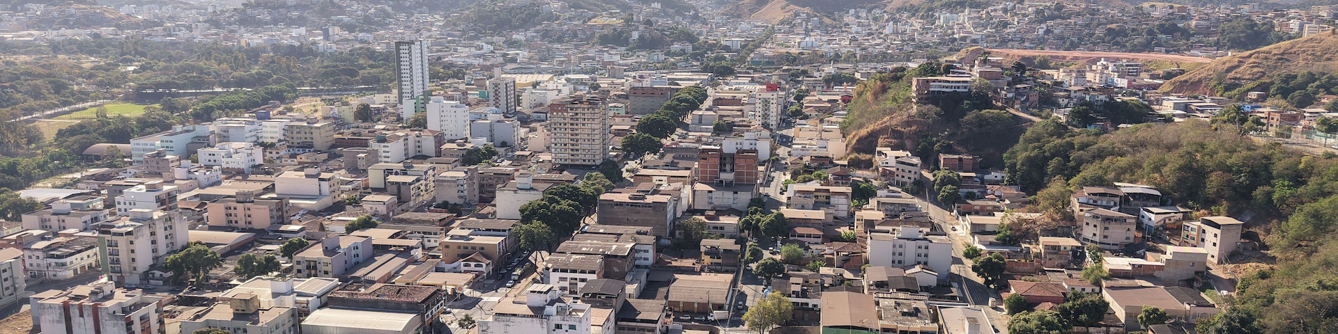 Una ciudad densamente construida con un edificio alto destacado y colinas circundantes.