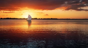 Un voilier sur une eau calme, au coucher du soleil, avec un ciel spectaculaire.
