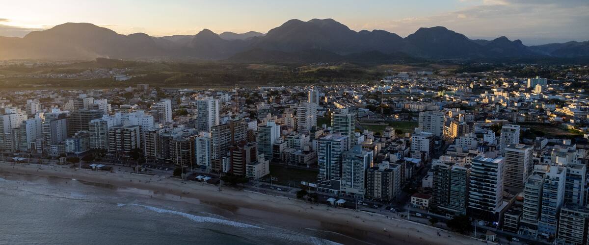 Drone view of Praia do Morro at sunset in Guarapari Brazil – golden light on buildings and Morro da Pescaria coastline