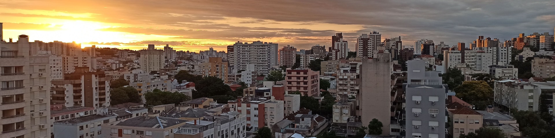 Paisaje urbano al atardecer con rascacielos y cielo nublado.