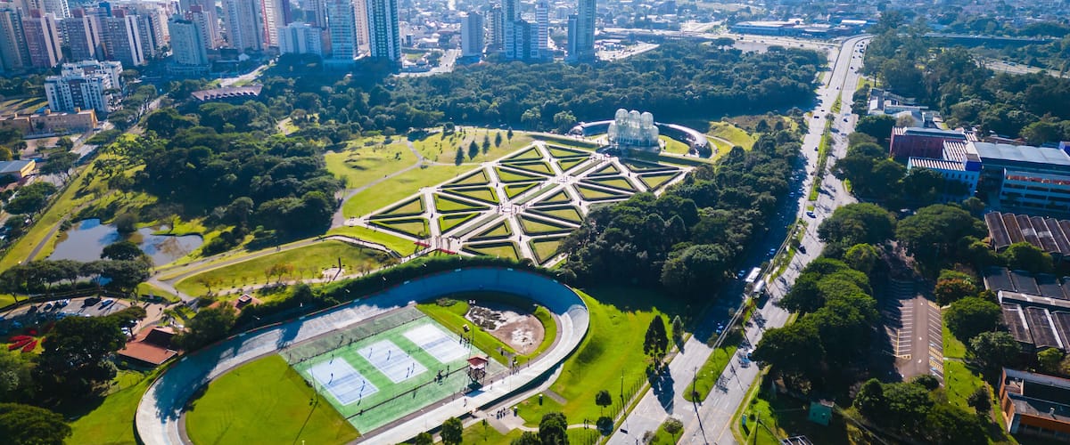 Vista aérea de uma cidade com um estádio grande, áreas verdes e edifícios altos.