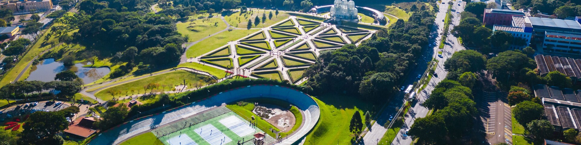 Vista aérea de uma cidade com um estádio grande, áreas verdes e edifícios altos.