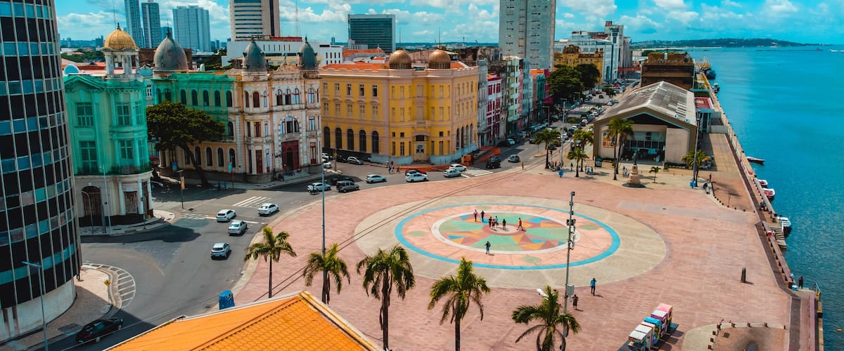 A coastal cityscape with historic buildings, a central plaza, and a waterfront.