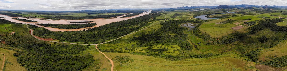 A river winding through a lush green valley with distant mountains under a partly cloudy sky.