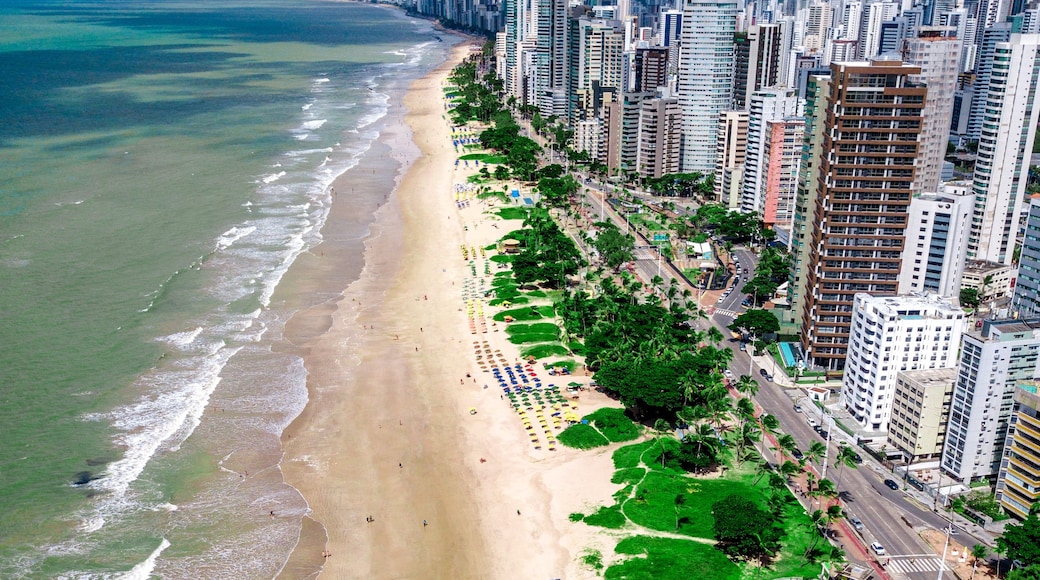 Paisagem costeira urbana com uma praia repleta de guarda-sóis coloridos e edifícios altos.