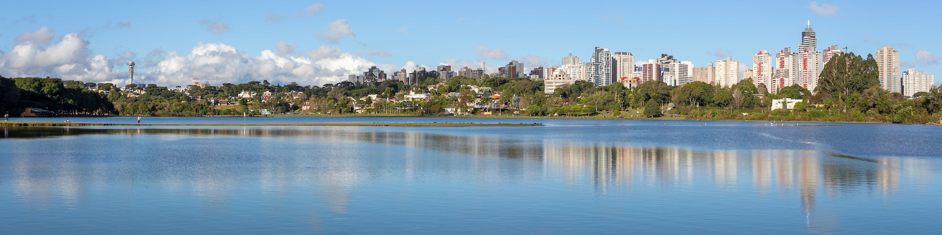Um lago tranquilo com o horizonte da cidade ao fundo.