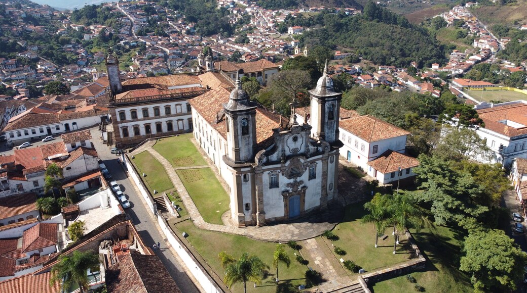 Un pueblo histórico con una iglesia destacada, que cuenta con un campanario y una cúpula, rodeado de casas escalonadas y abundante vegetación.