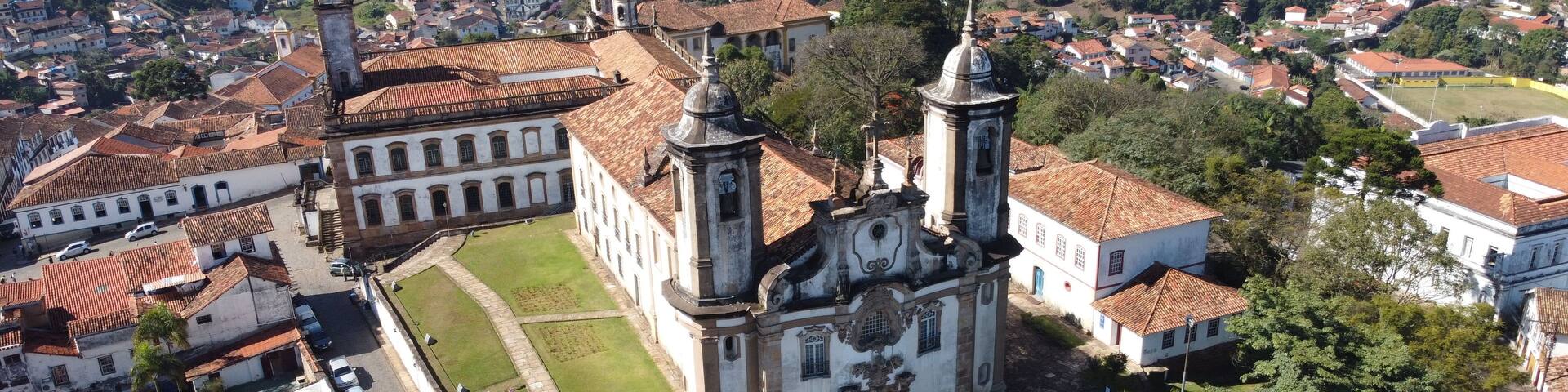 A historic town with a prominent church featuring a bell tower and dome, surrounded by terraced houses and lush greenery.
