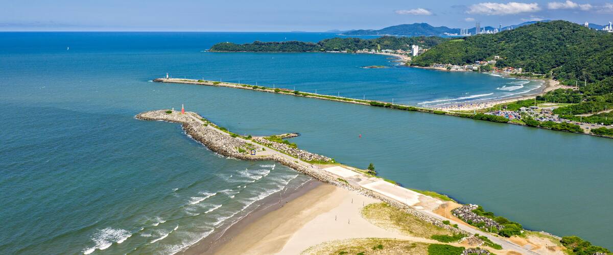 Aerial view of Itajai breakwater and Navegantes lighthouse with turquoise sea and green hills, Santa Catarina.