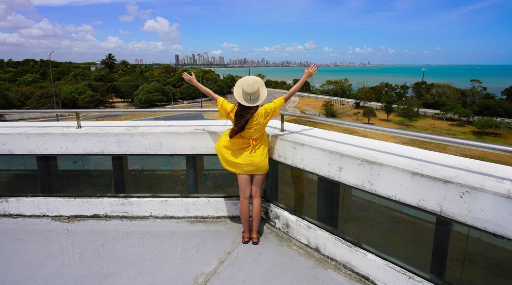 Visiting Joao Pessoa, Paraiba, Brazil. Back view of young woman with open arms on Estacao Cabo Branco viewpoint, Joao Pessoa, Brazil.