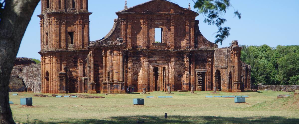 Una iglesia de ladrillo antiguo con dos campanarios y un amplio acceso principal.