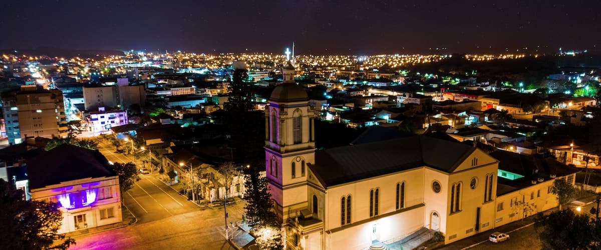 Un paisaje urbano nocturno con una imponente torre de iglesia y una calle iluminada.