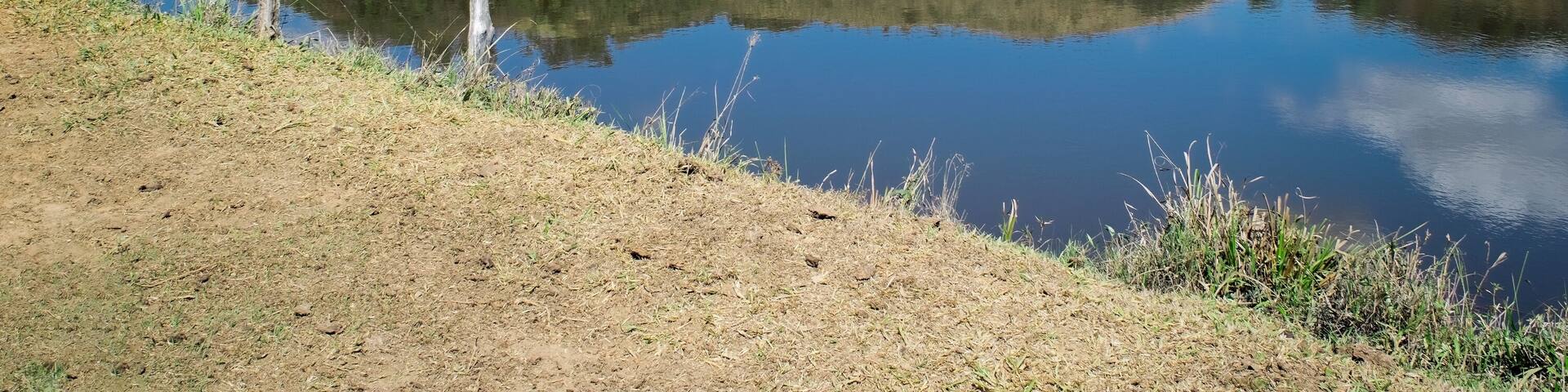 Paisagem de verão em fazenda, com muita vegetação ao redor, lindo lago, céu azul e nuvens, tudo em meio a montanhas, no bairro Jardim das Oliveiras, Esmeraldas, Minas Gerais, Brasil
