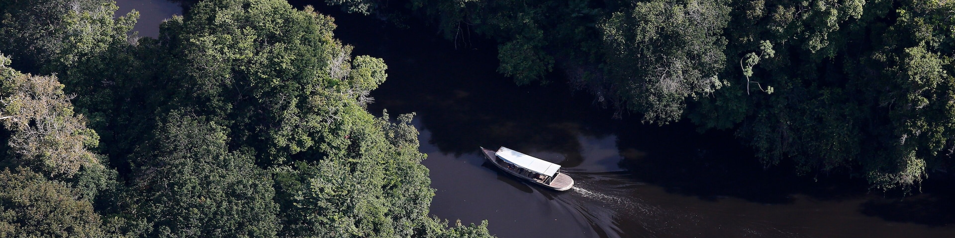 A boat on a river surrounded by dense forest.