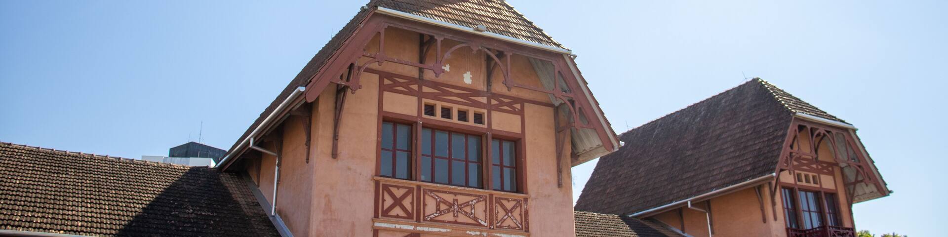A historic building with a clock tower, steeply pitched roof, and timber framing.