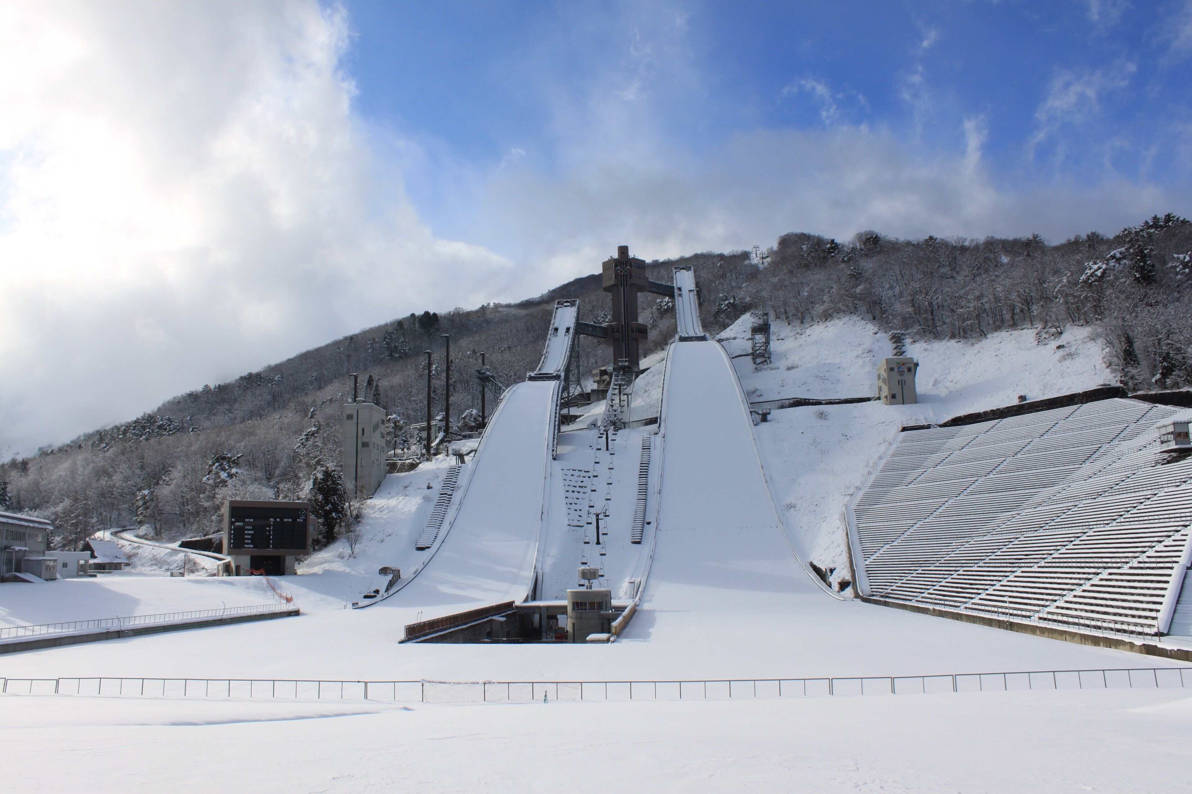 A snow-covered ski lift with a control tower and a mountain backdrop.