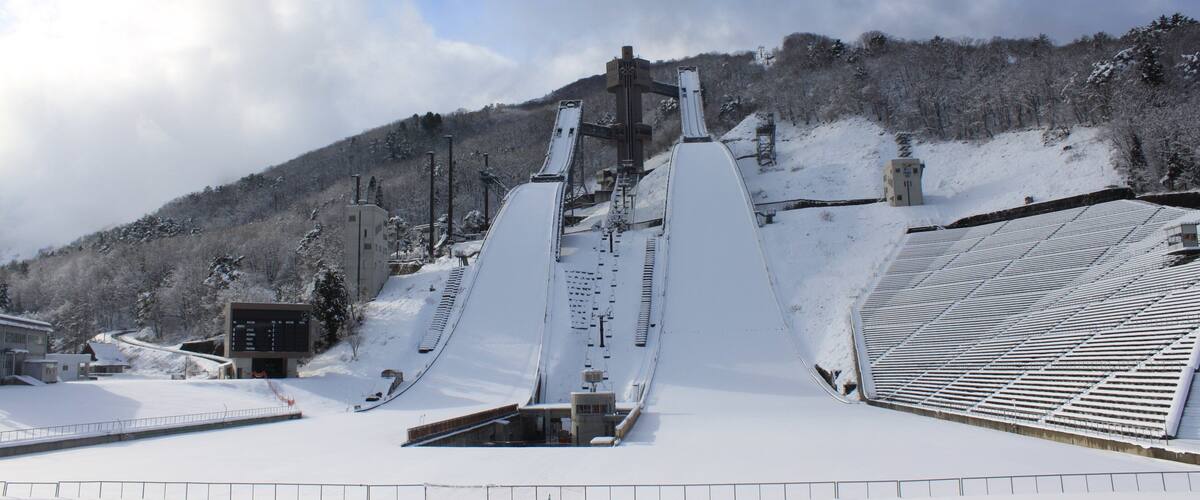 A snow-covered ski lift with a control tower and a mountain backdrop.