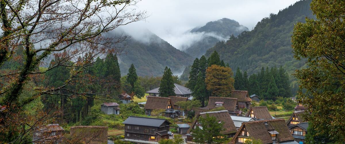A village with traditional thatched-roof houses nestled in a valley surrounded by mountains.