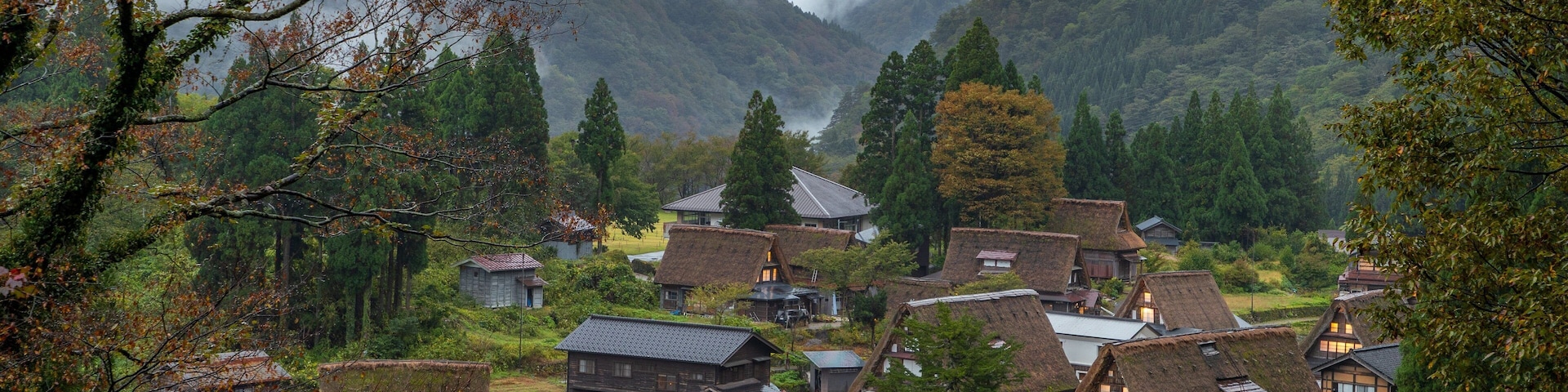 A village with traditional thatched-roof houses nestled in a valley surrounded by mountains.