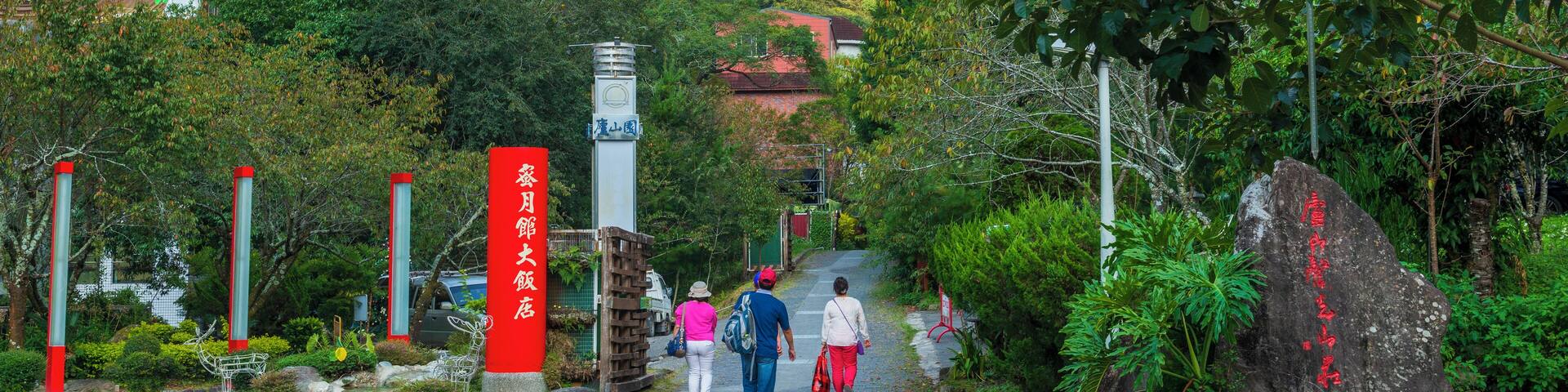 A pathway leading uphill with a signpost, a large rock with red text, and lush greenery.