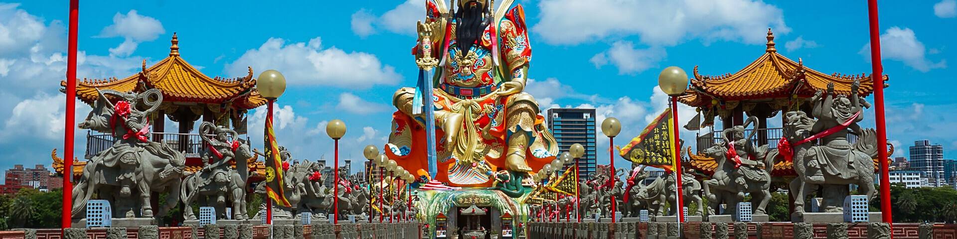 Una estatua dorada imponente de una deidad, flanqueada por edificios y estatuas decorativas.
