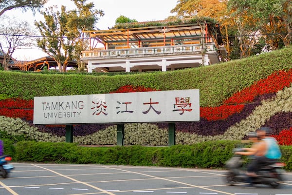 Une enseigne de l’université de Tamkang, avec un jardin fleuri aux couleurs vives en arrière-plan.