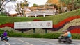 Une enseigne de l’université de Tamkang, avec un jardin fleuri aux couleurs vives en arrière-plan.