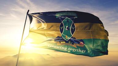 A flag with the text "Murang'a County" and "Growing together" against a sunrise sky.